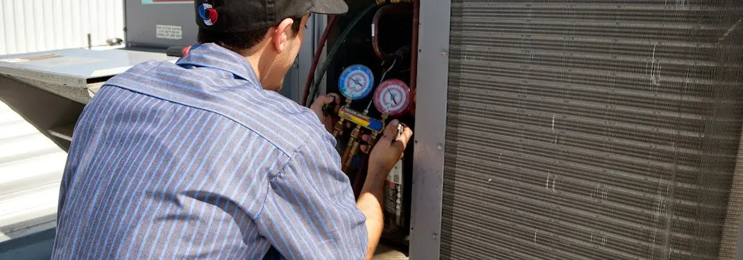HVAC technician servicing a condenser unit in San Luis